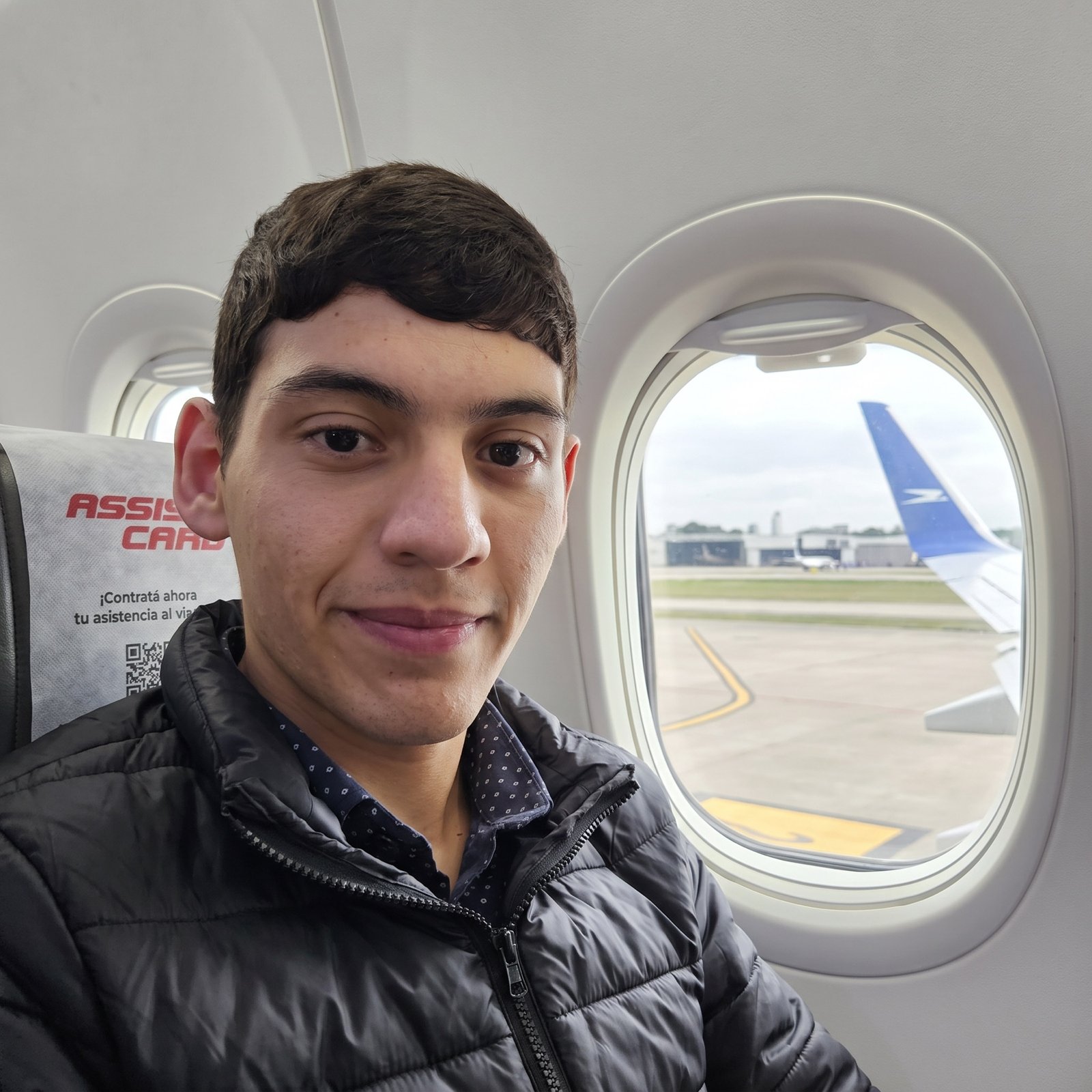 Facu sonriendo en el asiento de un avión antes de despegar